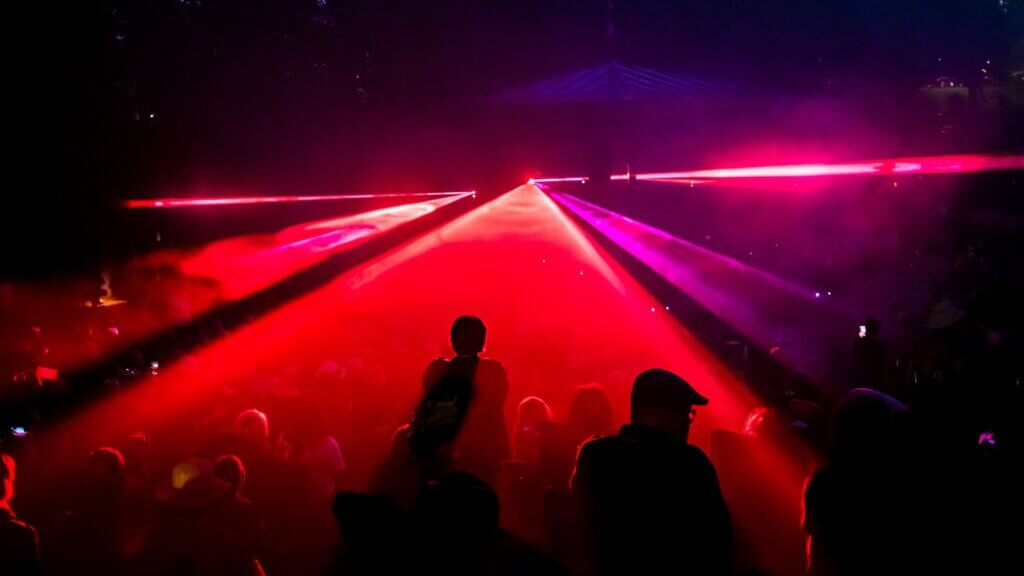 People dancing under red laser lights at a concert