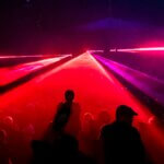 People dancing under red laser lights at a concert