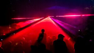 People dancing under red laser lights at a concert